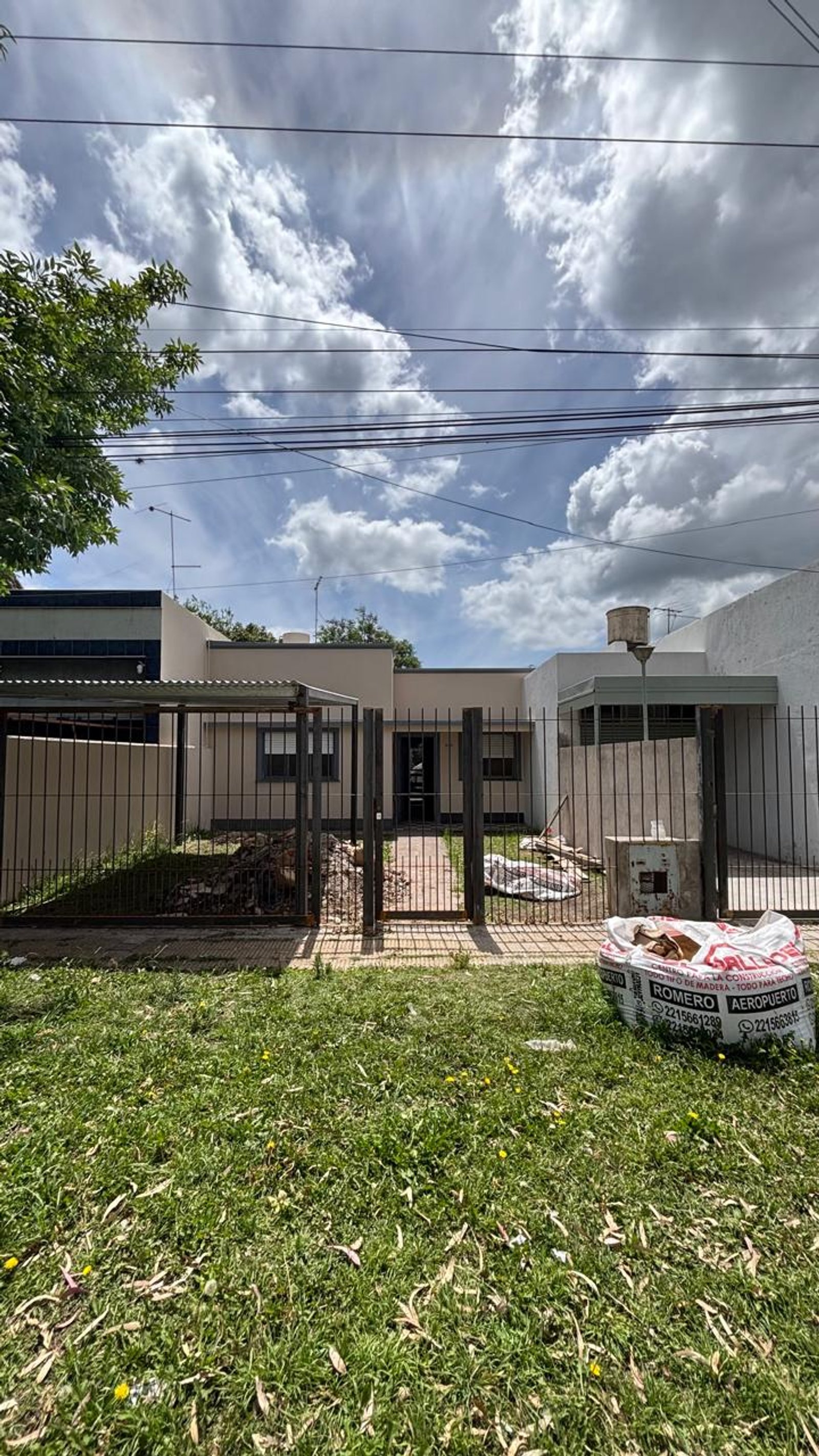 Fachada de casa moderna suburbana com gramado e saco de materiais — projeto REFORMA C520, por Estudio Llobet, em Melchor Romero
